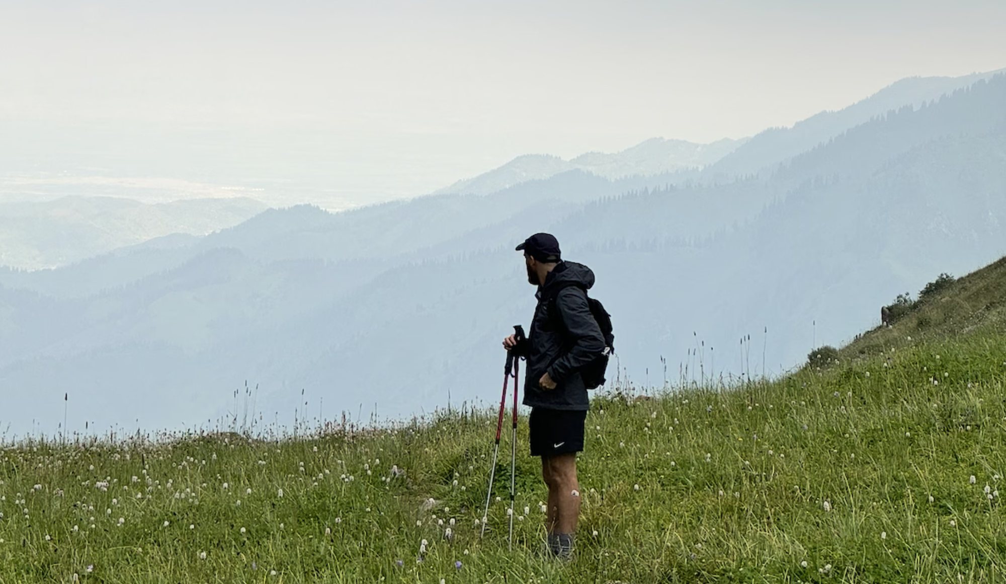 Stéphane hiking on a grassy mountainside, looking out over misty valleys